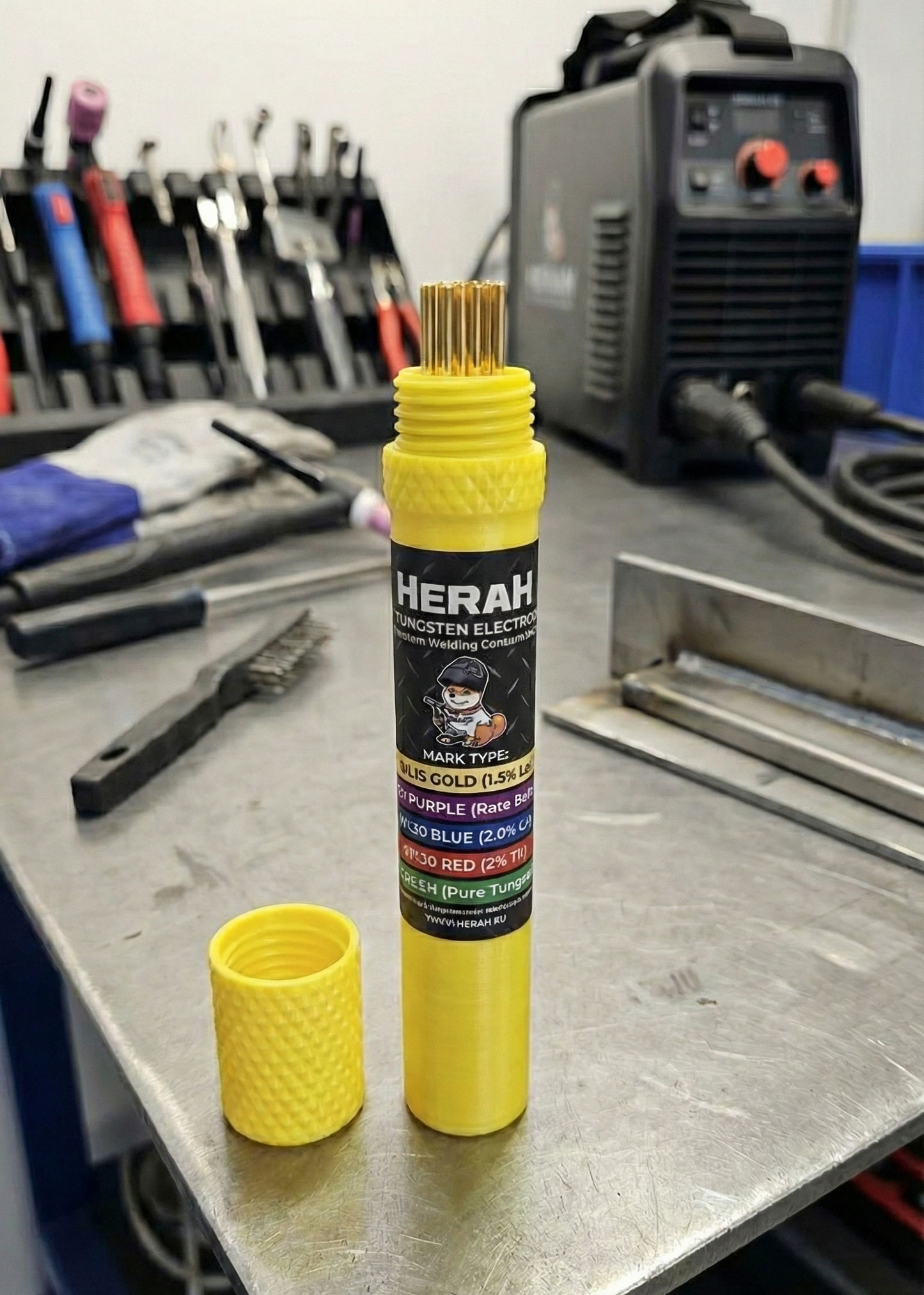 Yellow cylindrical product with tig tungsten 'HERAH' branding on a workshop table.